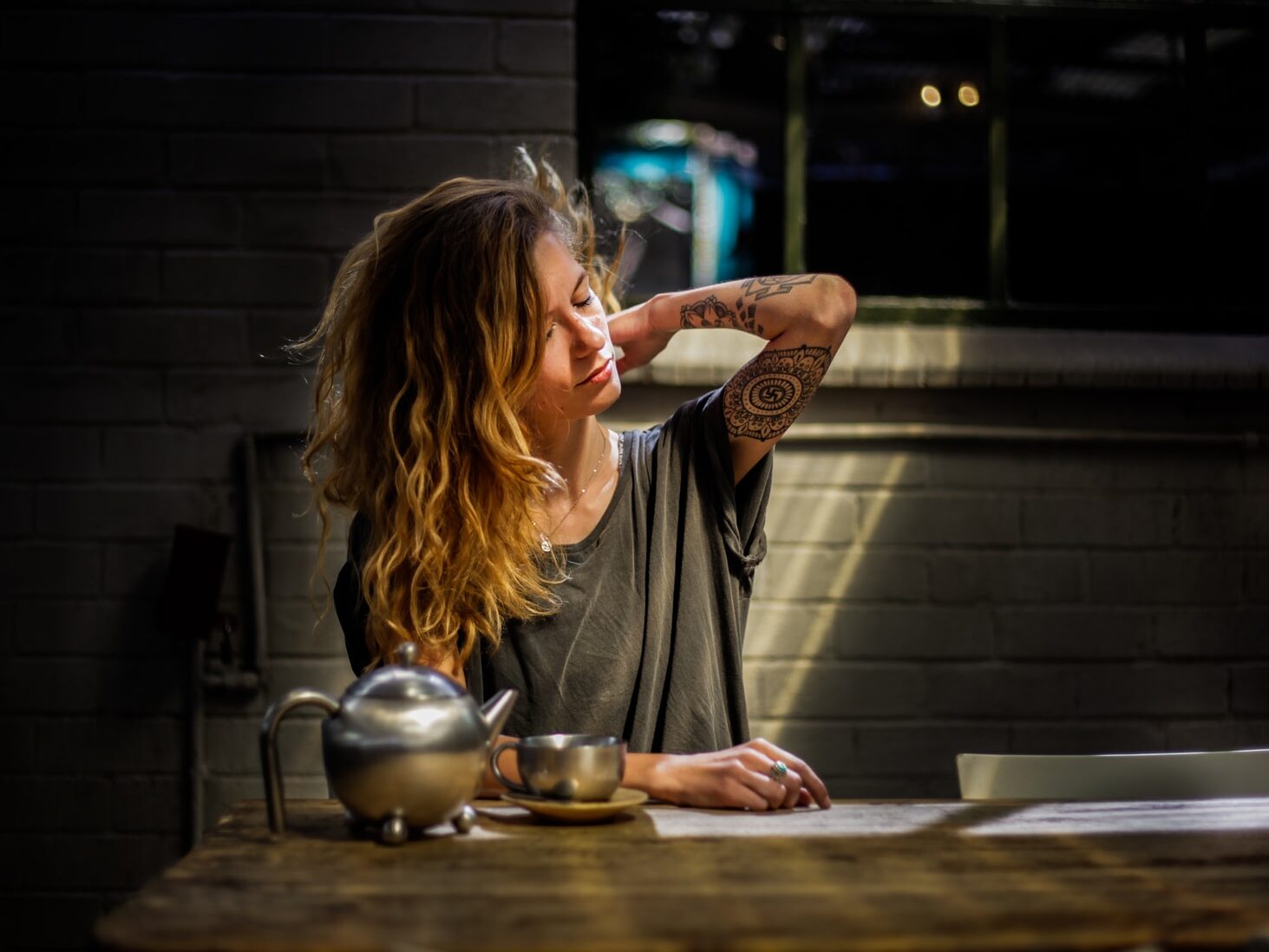 - ČasProŽeny.cz woman in gray top sitting beside gray tea pot and cup on brown wooden table