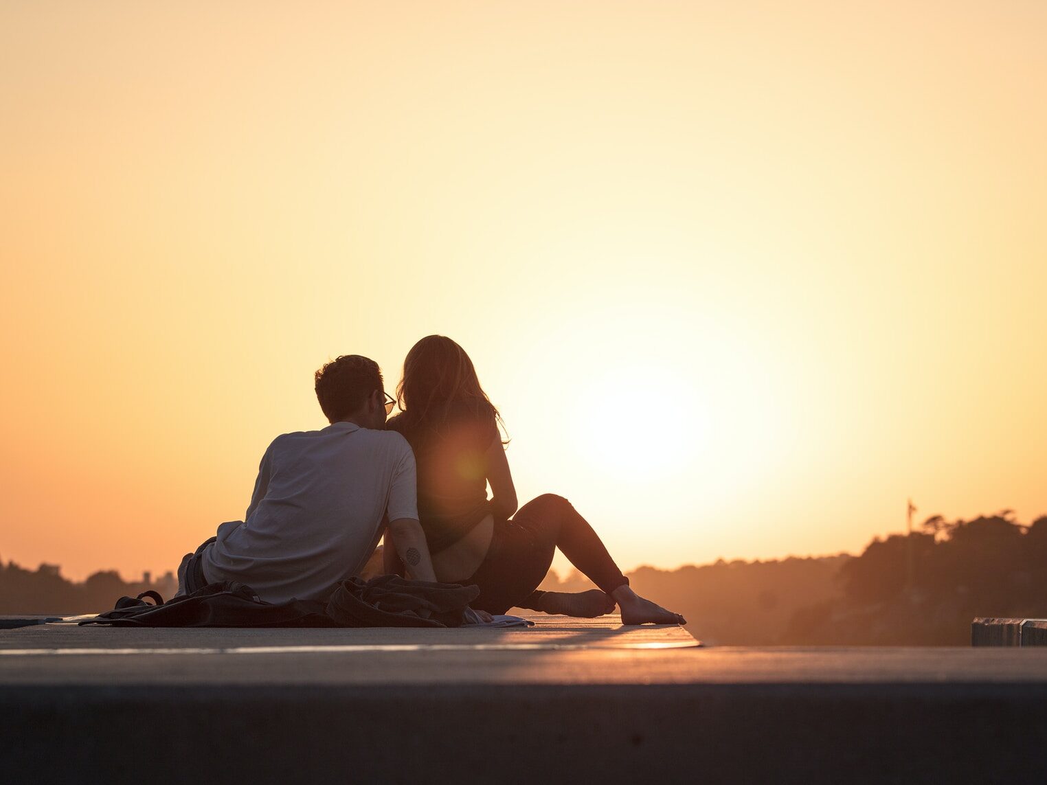 couple sitting near trees during golden hour