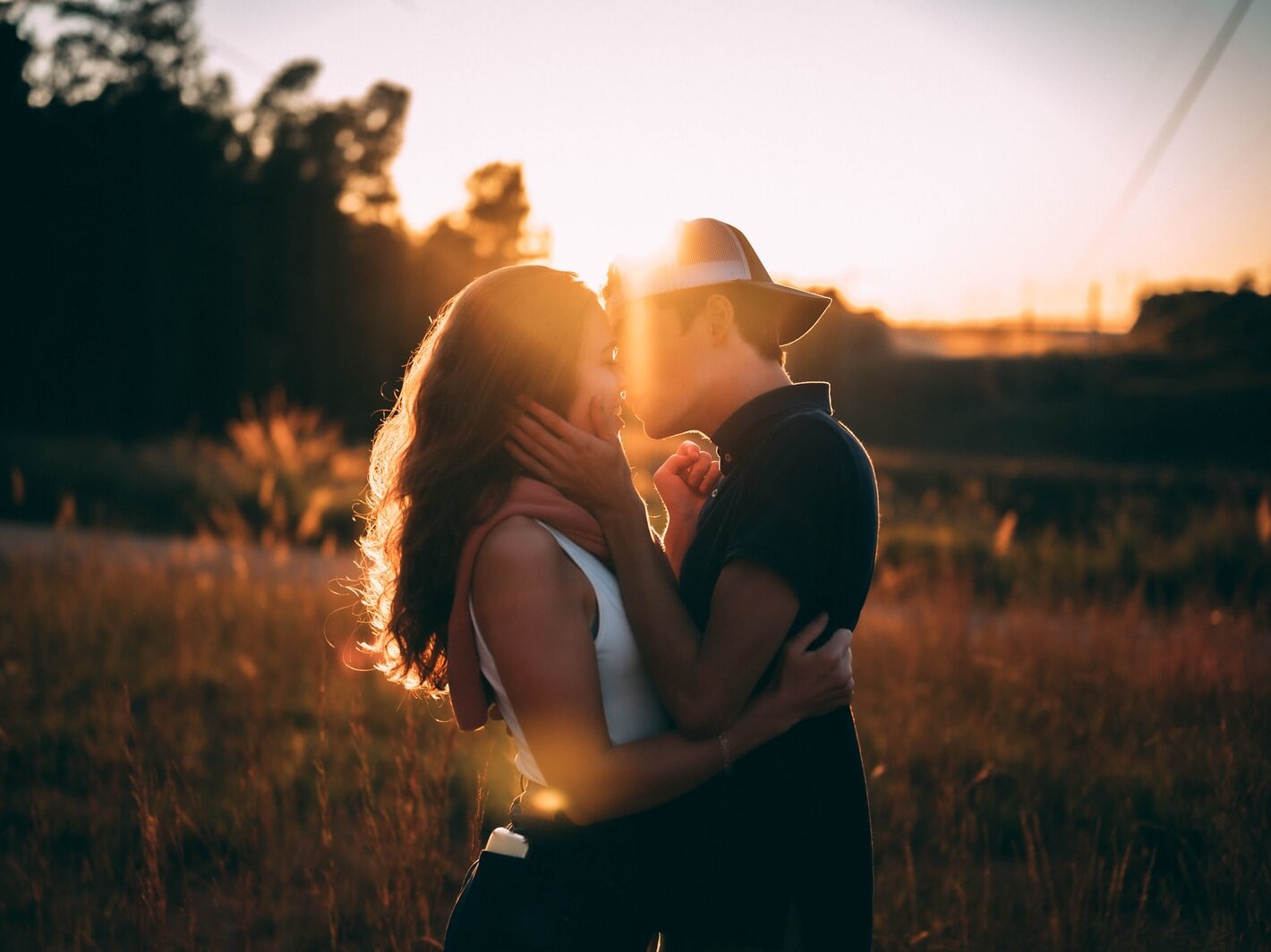 man and woman kissing during sunset
