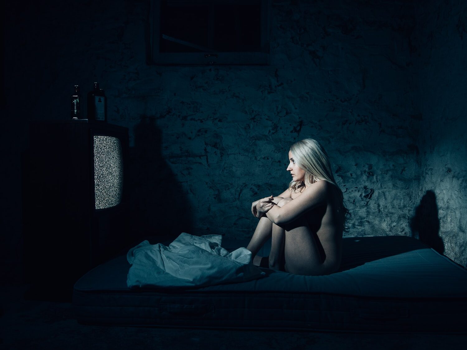 woman in black brassiere and panty sitting on bed