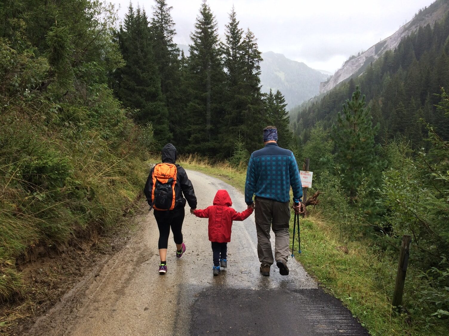 man, woman, and child walking together along dirt road