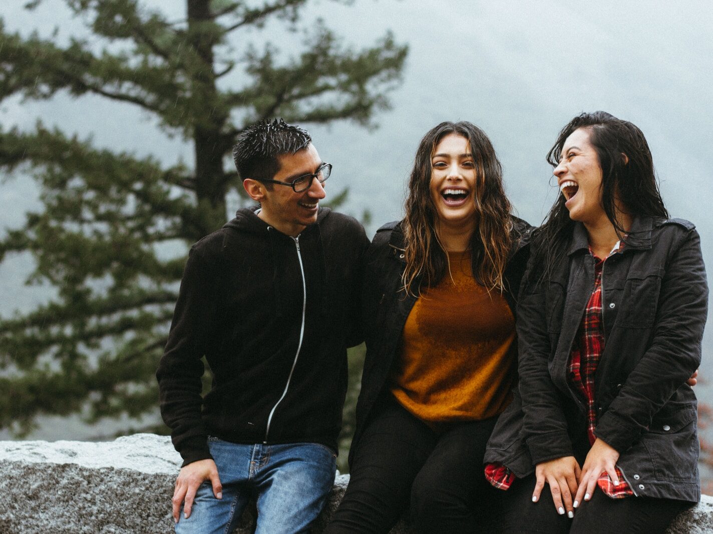 man sitting beside two woman on gray surface