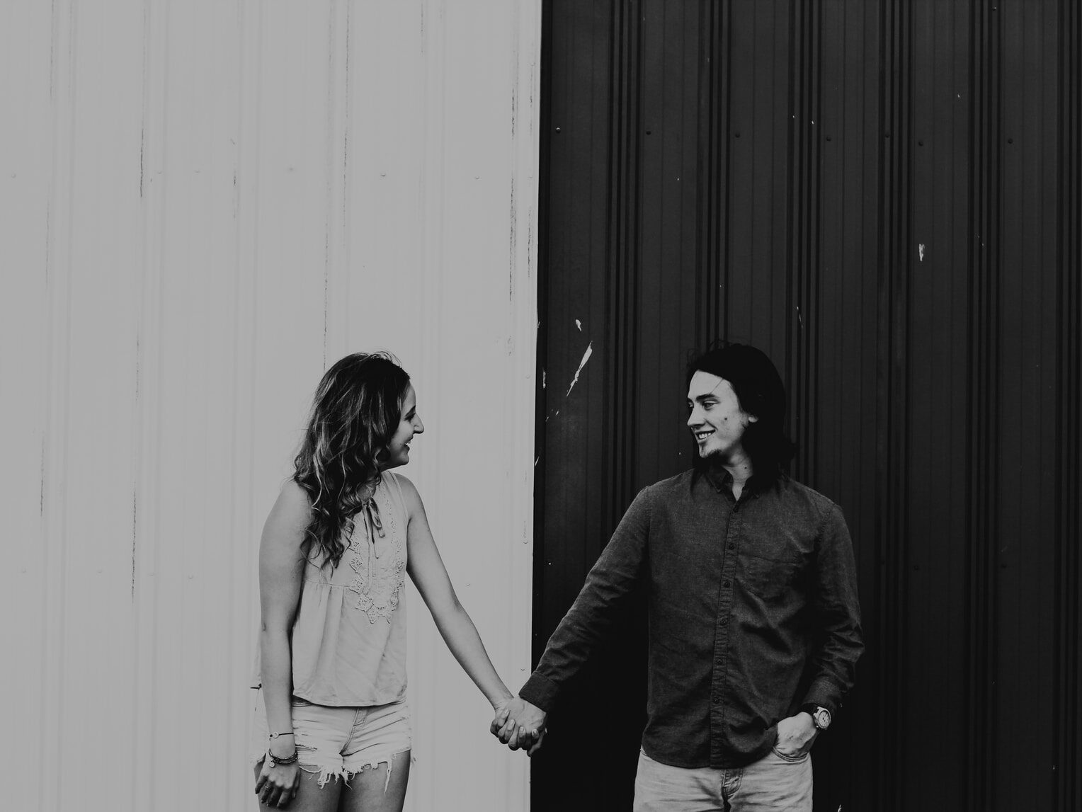man and woman holding hands in grayscale photography