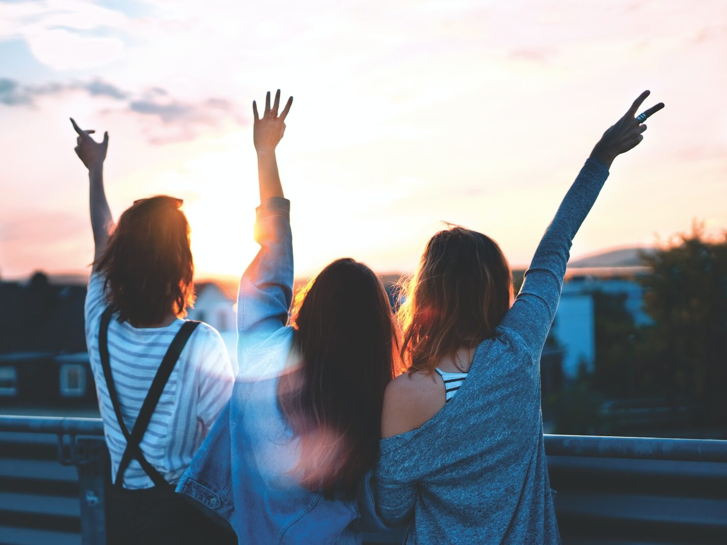 photo of three women lifting there hands 