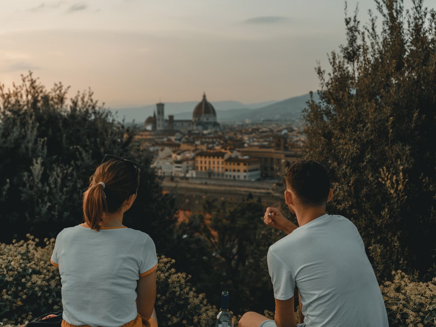 woman and man wearing white shirt while sitting near green trees during daytime