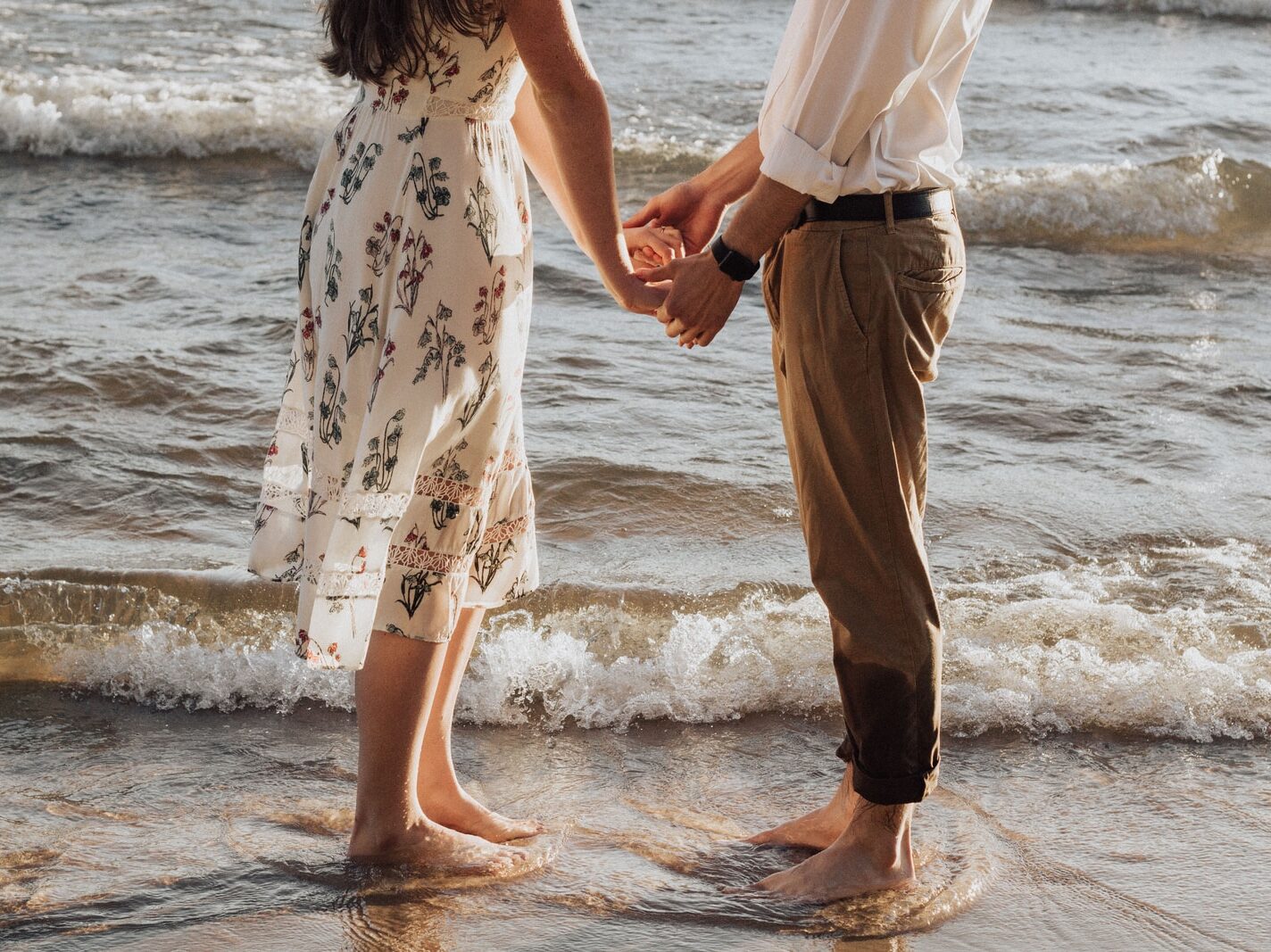 woman holding hands in front of man standing on seashore