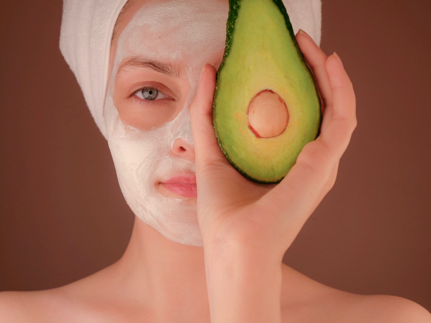 woman with white face mask holding green fruit