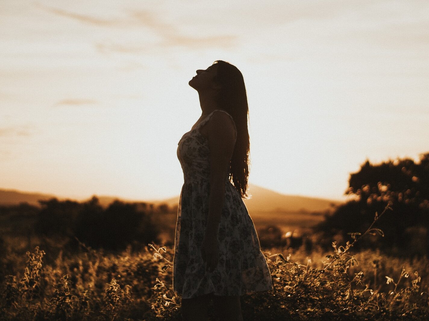woman wearing floral dress standing on brown grassland