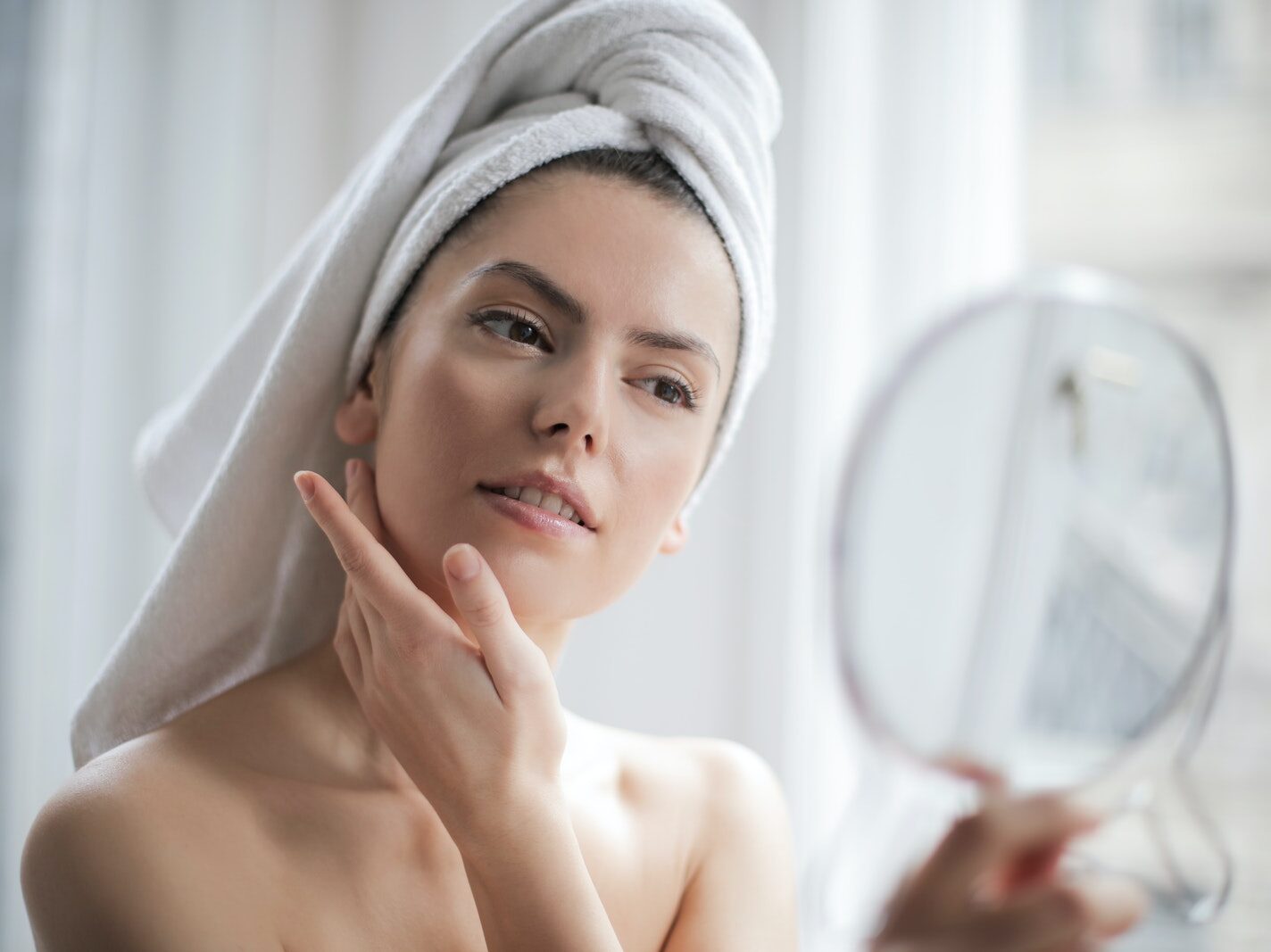 Selective Focus Portrait Photo of Woman With a Towel on Head Looking in the Mirror