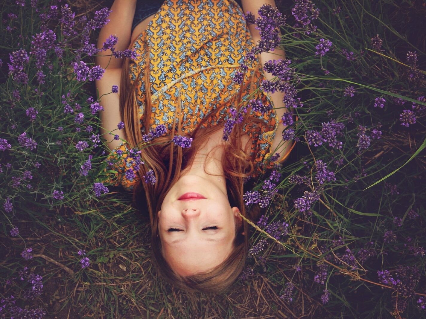 woman in yellow and teal top sleeping beside lavenders