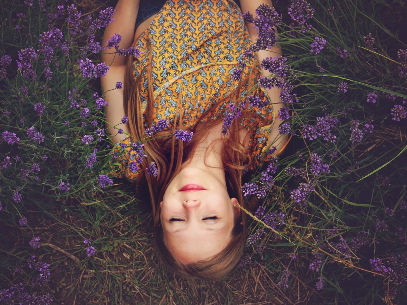 woman in yellow and teal top sleeping beside lavenders