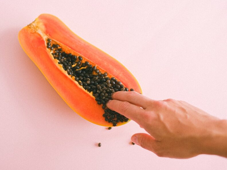 Crop unrecognizable woman touching ripe cut papaya