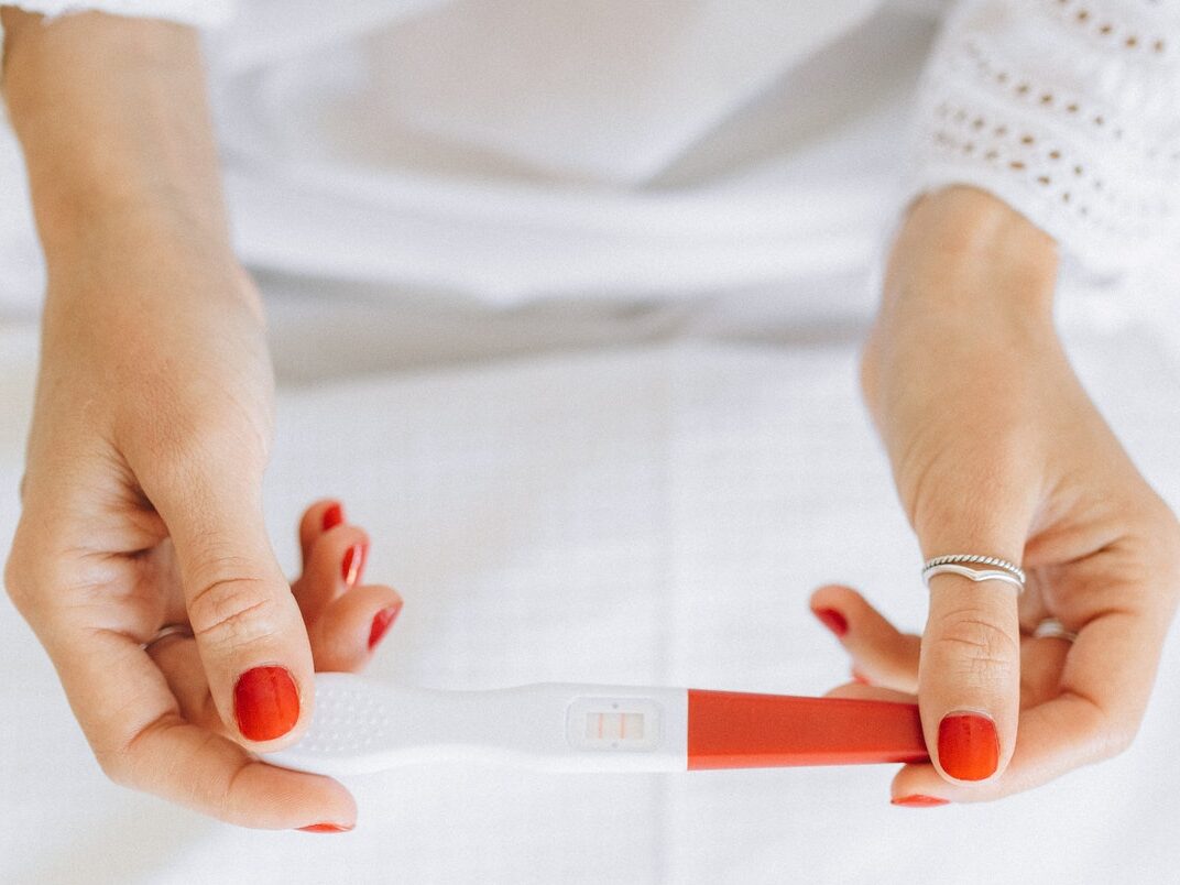 Person Wearing Silver Ring Holding White and Red Paper