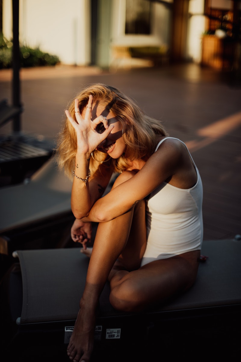 Woman in White Tank Top Sitting on Black Leather Couch