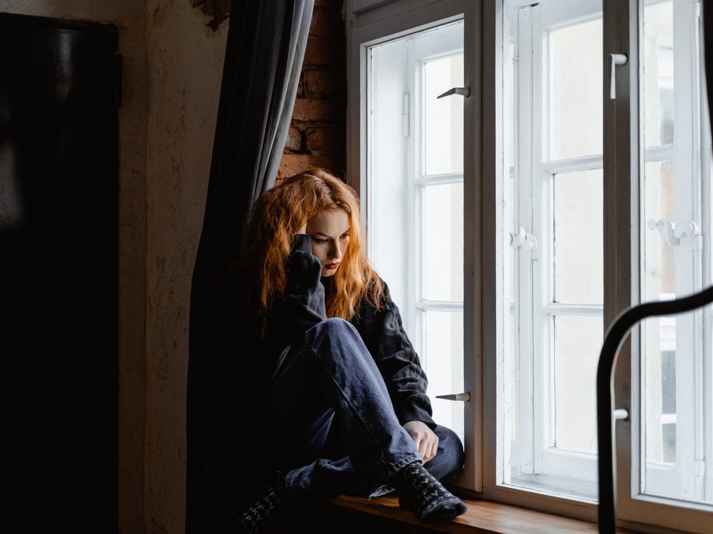 Woman in Black Leather Jacket Sitting on Brown Wooden Floor