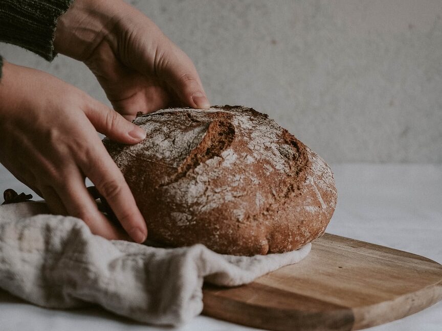- ČasProŽeny.cz person holding brown bread on brown wooden chopping board