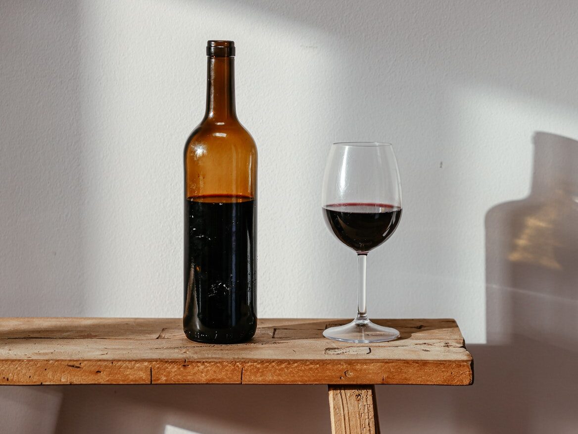 A Bottle and a Glass of Wine on a Wooden Bench