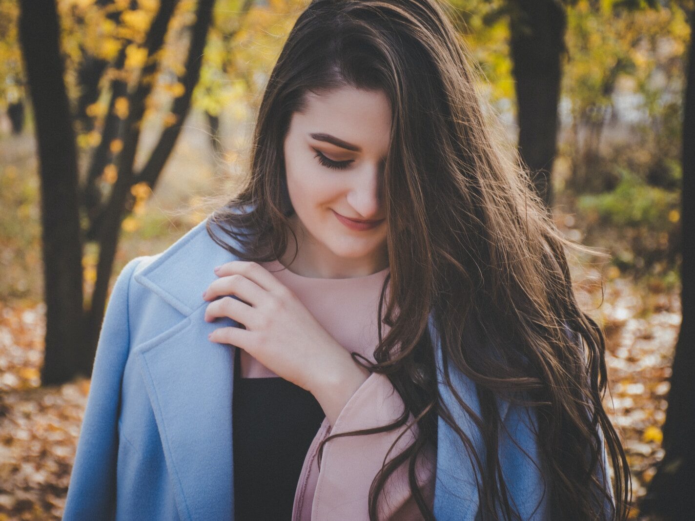 smiling woman near green trees selective focus photography