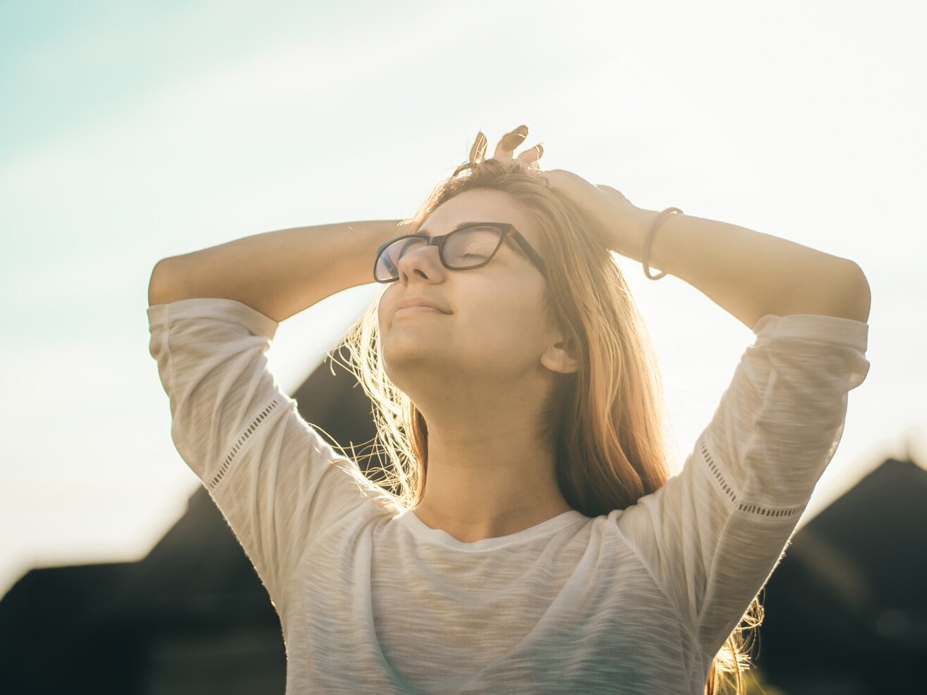 woman in white crew-neck T-shirt holding her head