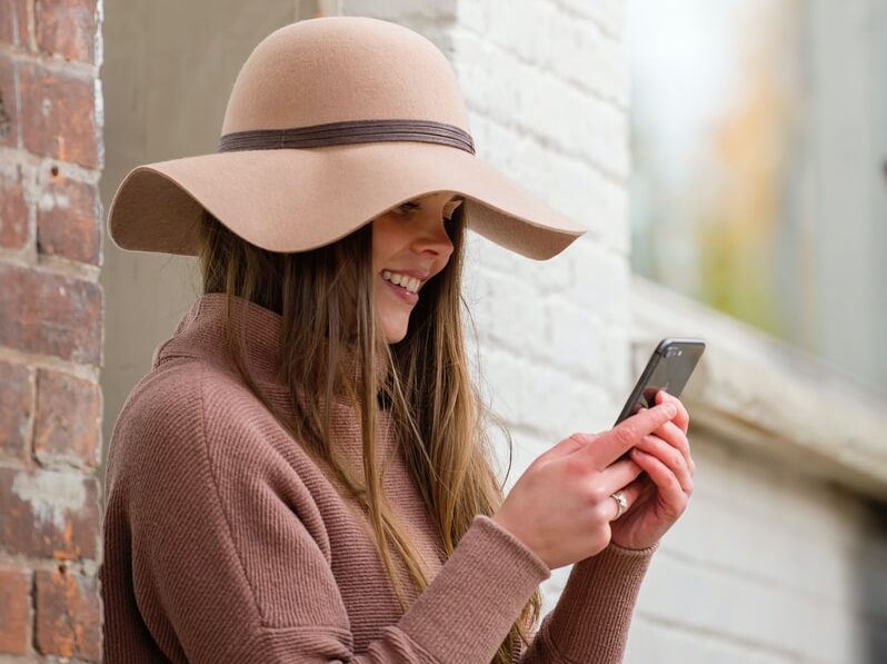 woman in brown hat and brown sweater holding smartphone