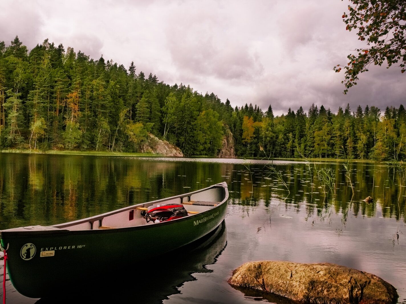 red and white canoe on lake near green trees under white clouds during daytime