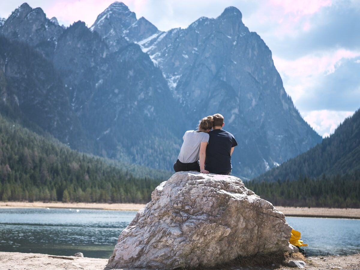 - ČasProŽeny.cz a couple sits on a rock looking out over a lake