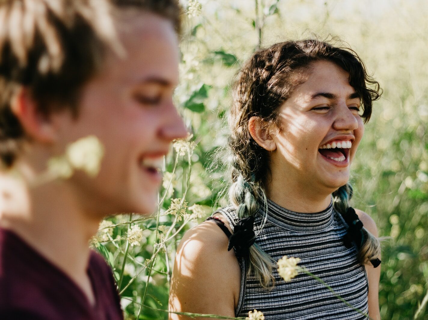 man and woman laughing surrounded with green grass during daytime