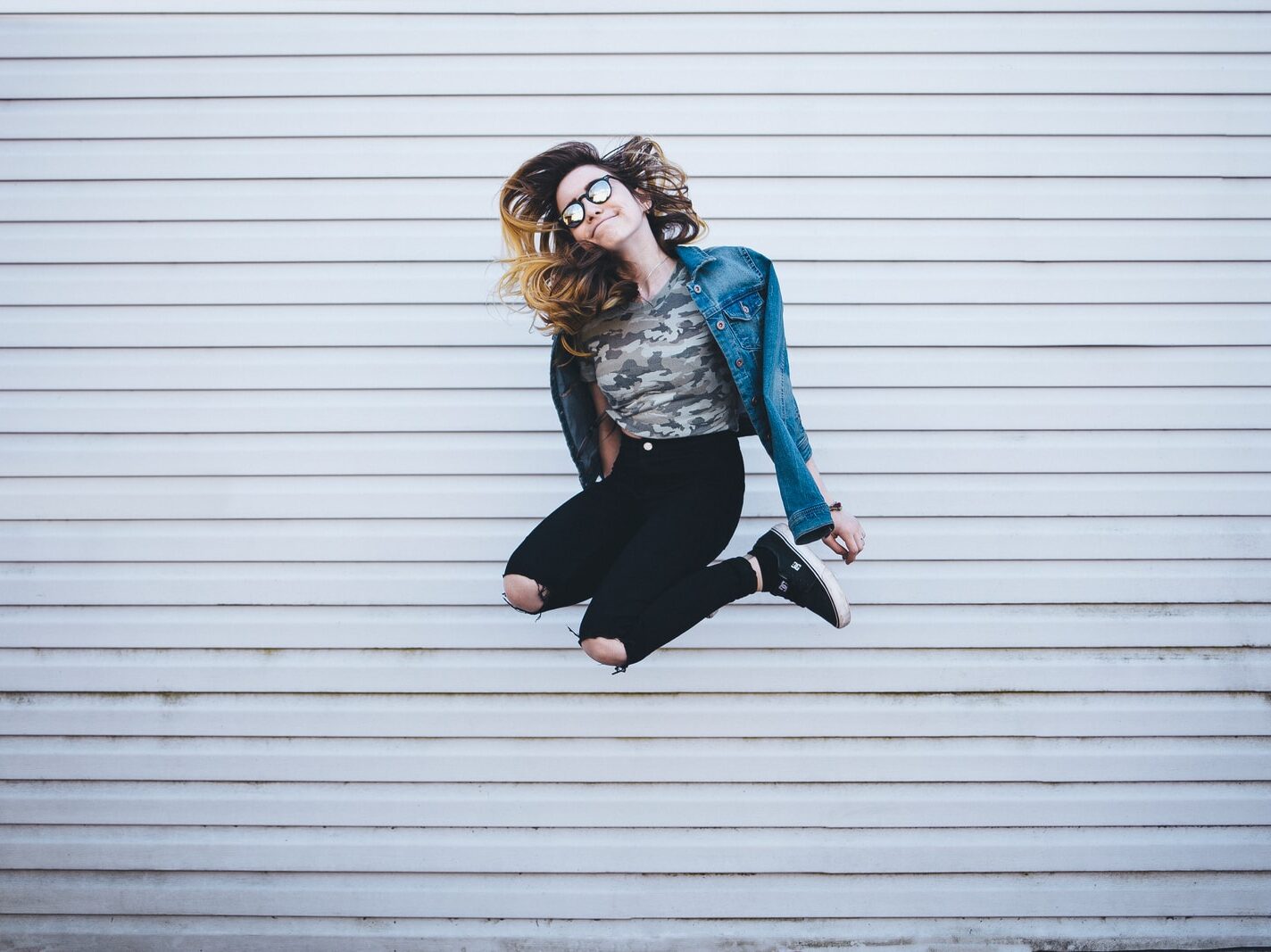 woman jumping in front of white concrete establishment