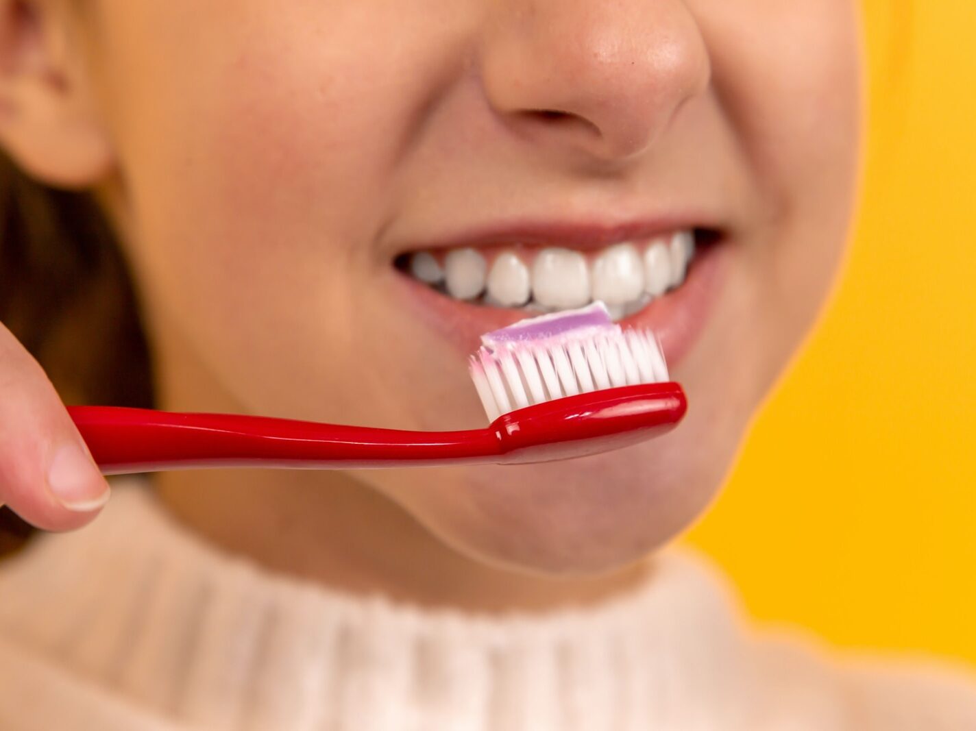 girl with red and white toothbrush in mouth