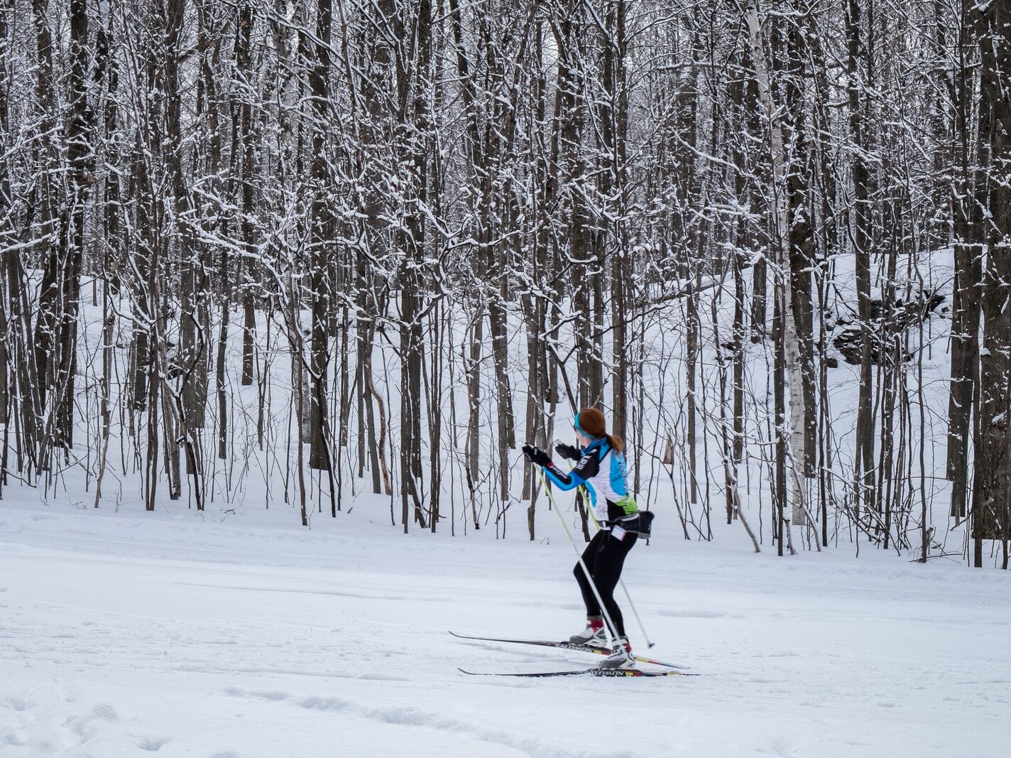 2 person in green jacket and black pants riding ski blades on snow covered ground during