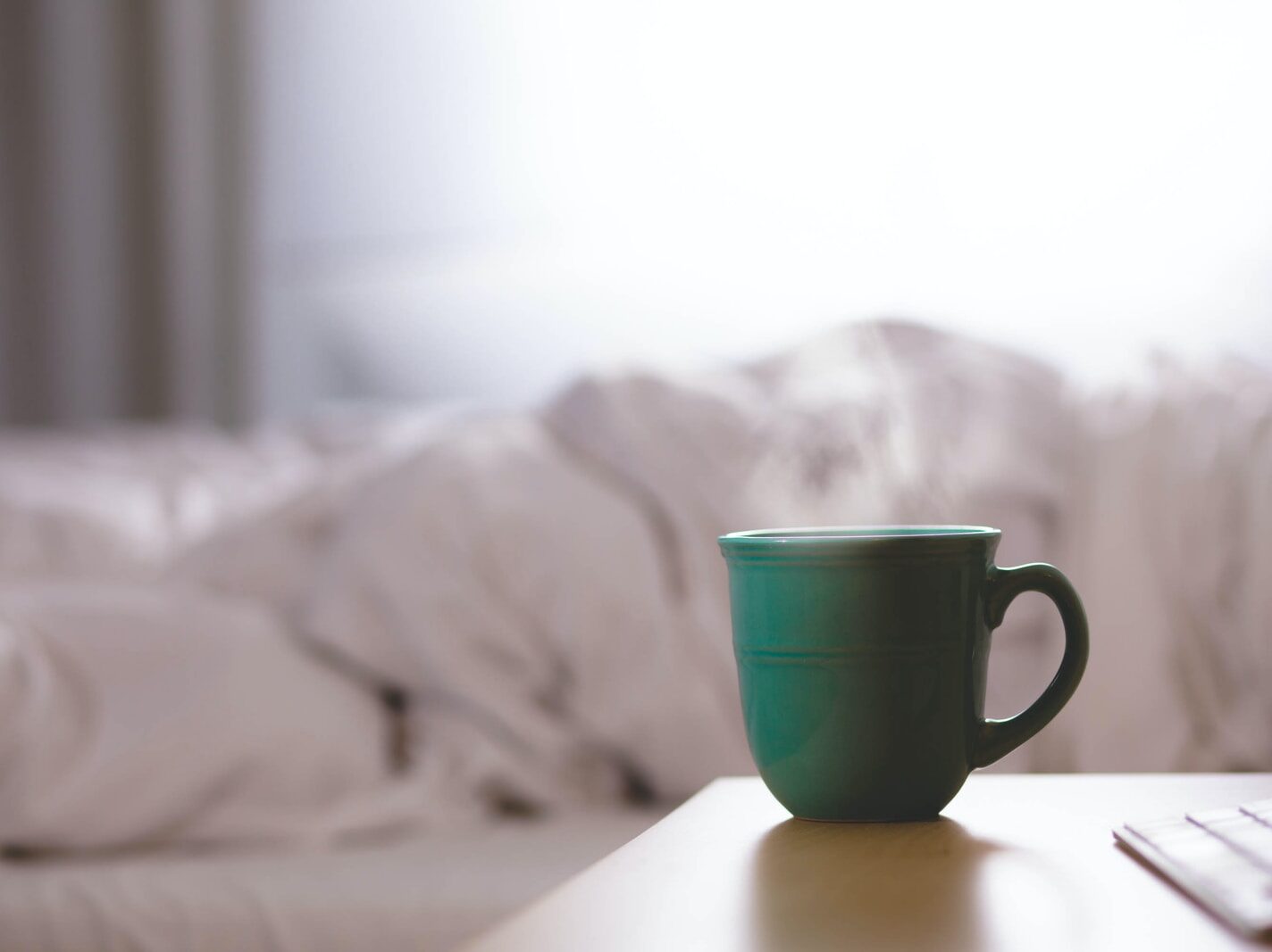 green ceramic mug on wooden desk