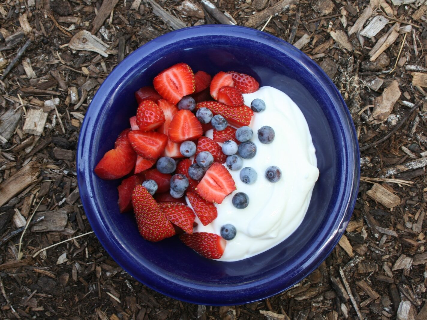 white ice cream with strawberries on blue plastic container