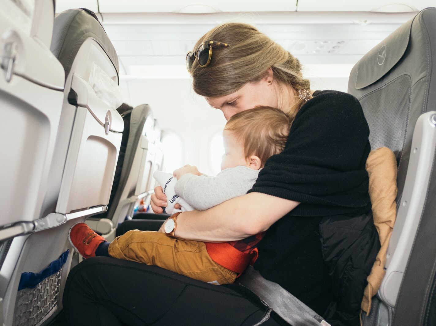 woman carrying baby while sitting on gray seat