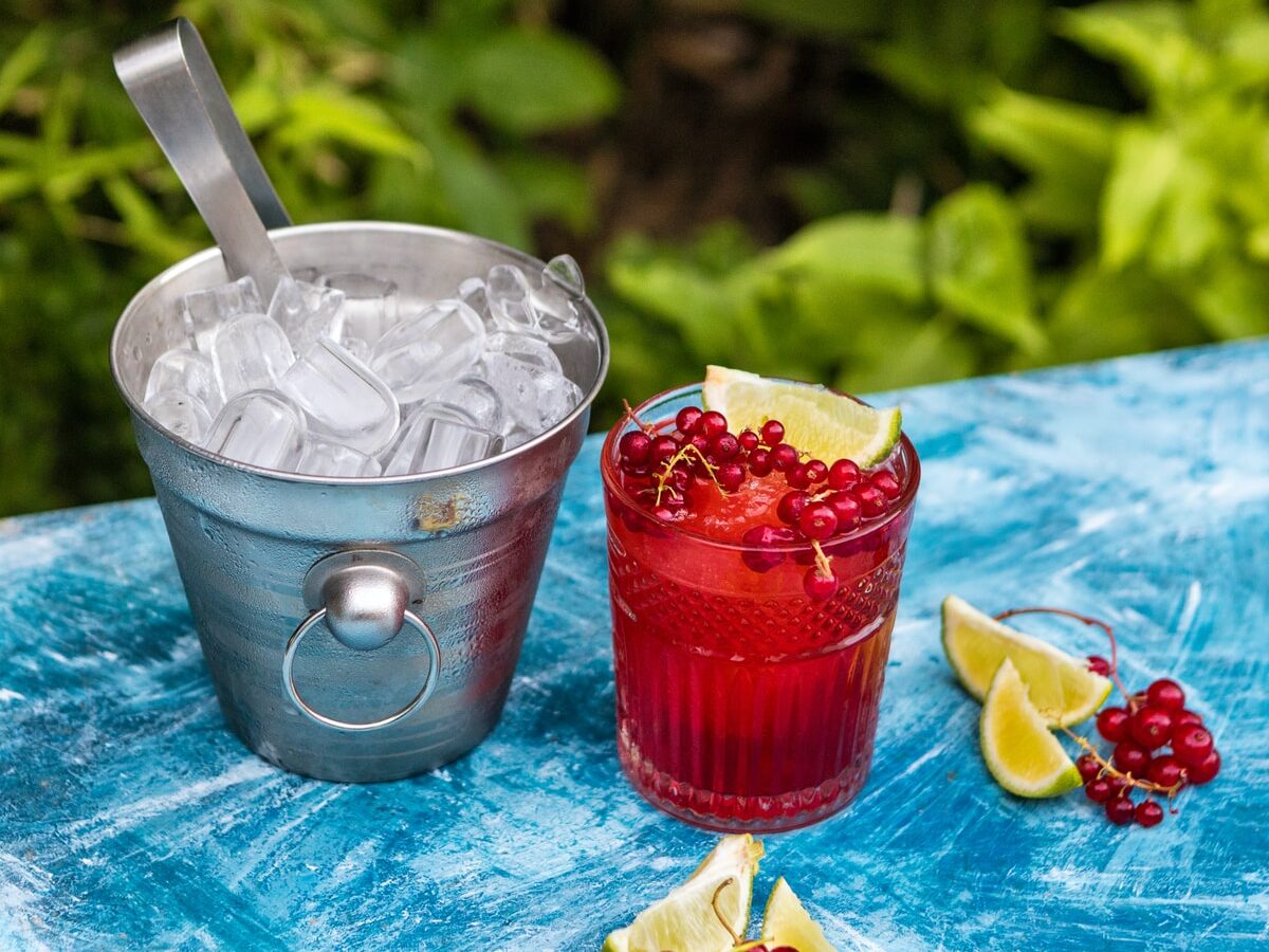ice cream in clear drinking glass with strawberry and white cream on blue table