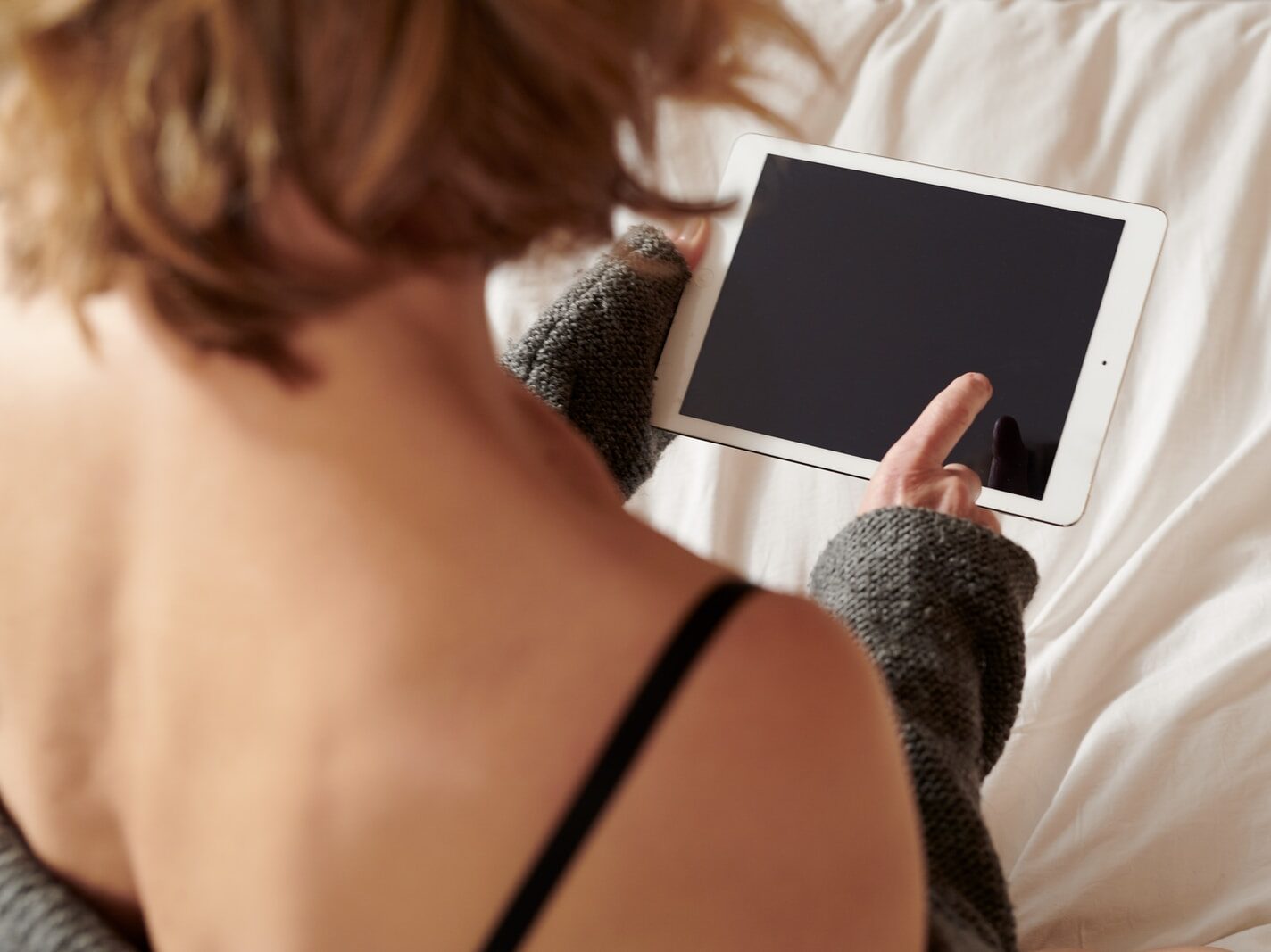 woman in black brassiere holding white ipad