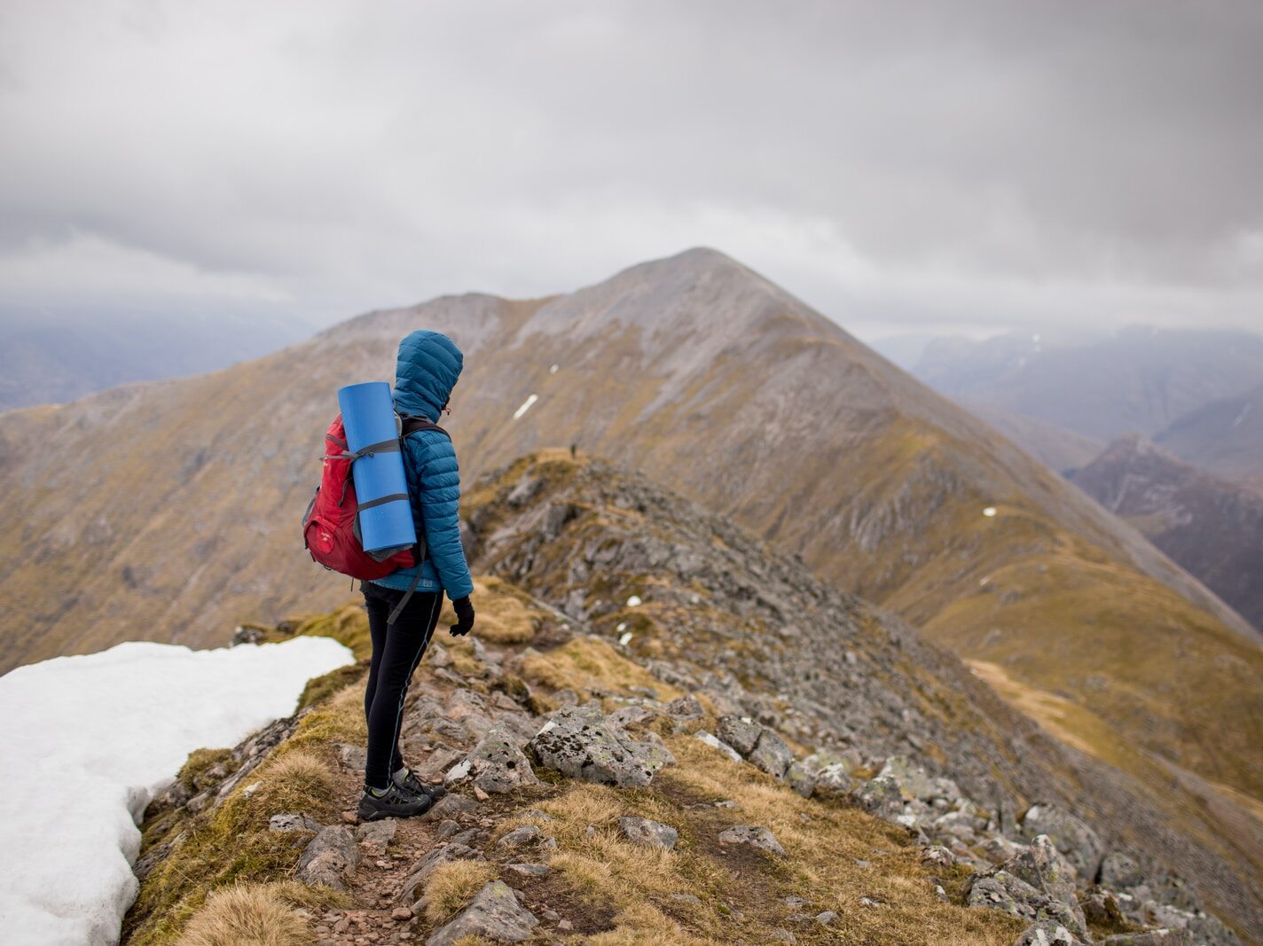 person at peak of mountain carrying red backpack