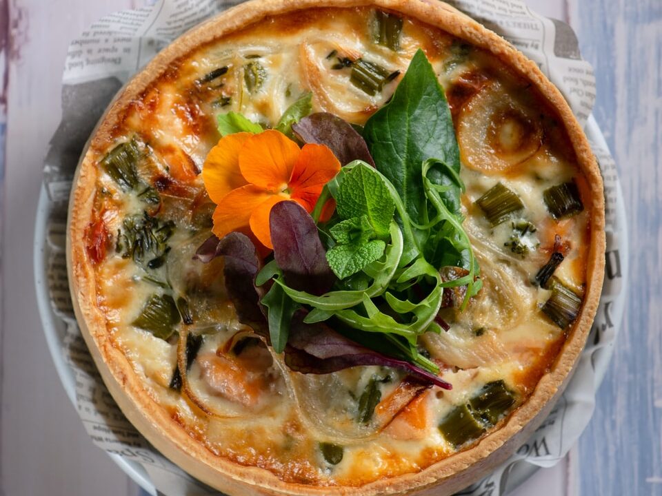 pizza with green leaf vegetable on white ceramic plate