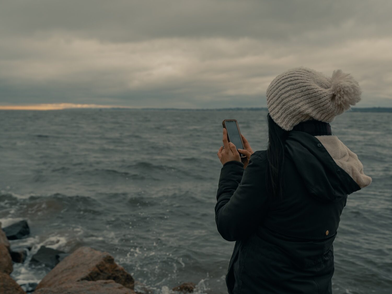 man in black jacket taking photo of sea during daytime