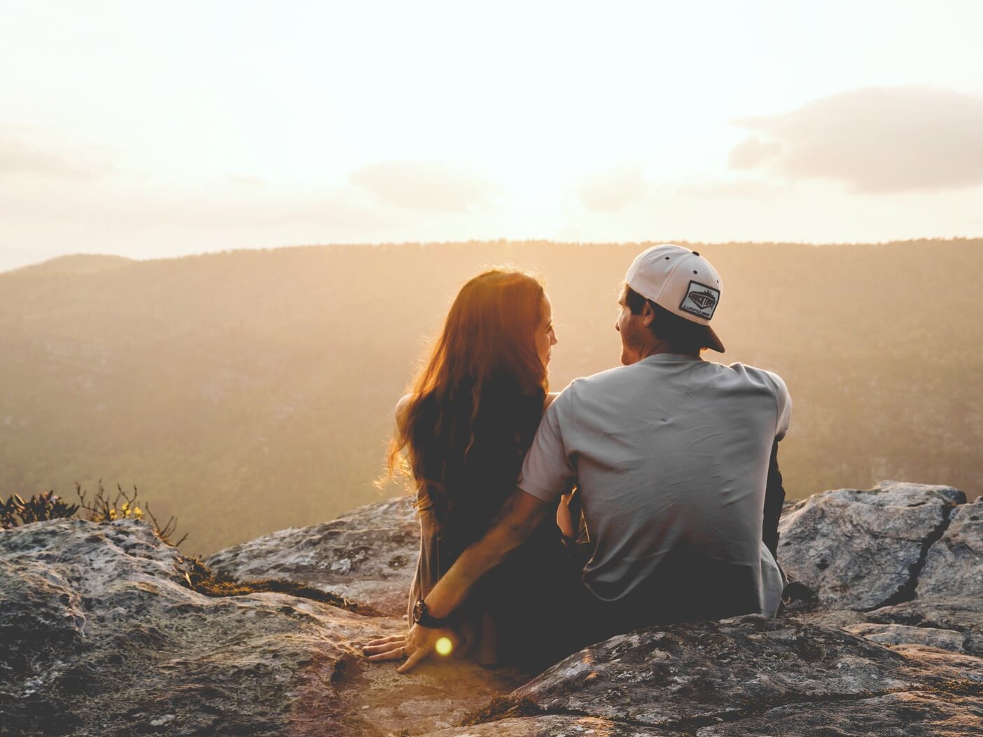 man and woman sitting on rock during daytime