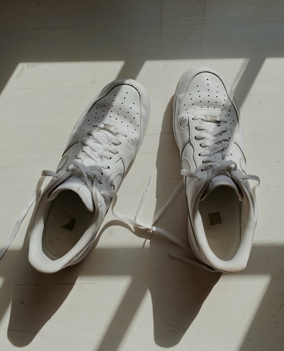 white nike sneakers on white wooden table