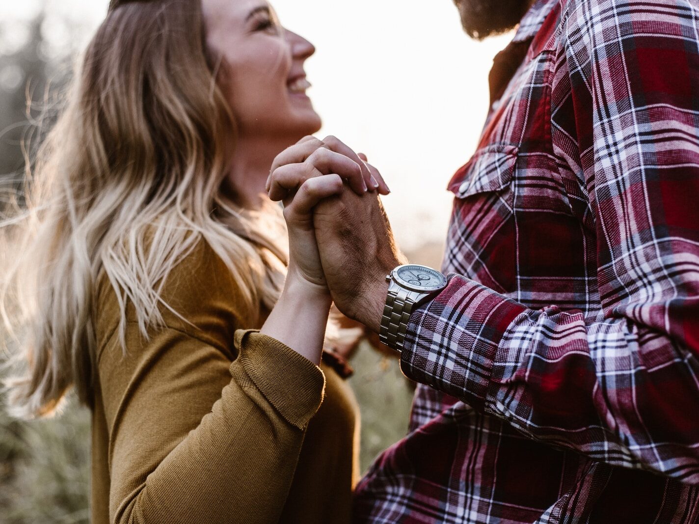 woman in front of man holding each hands each other near green trees