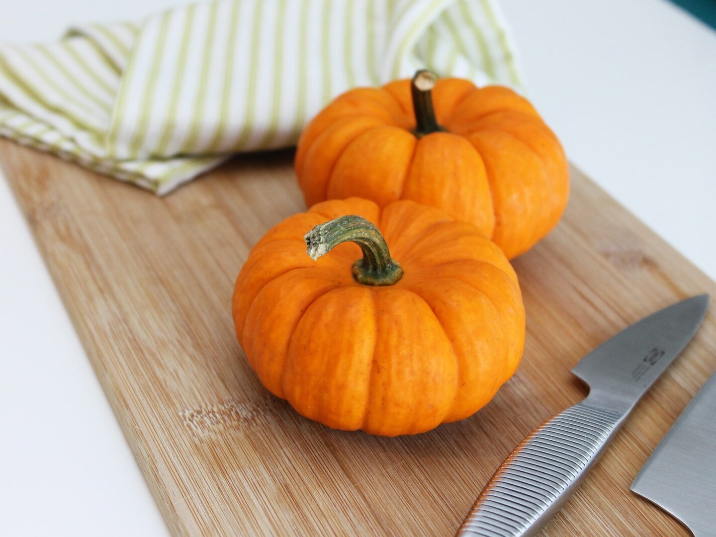 selective focus photography of two pumpkins placed on chopping board