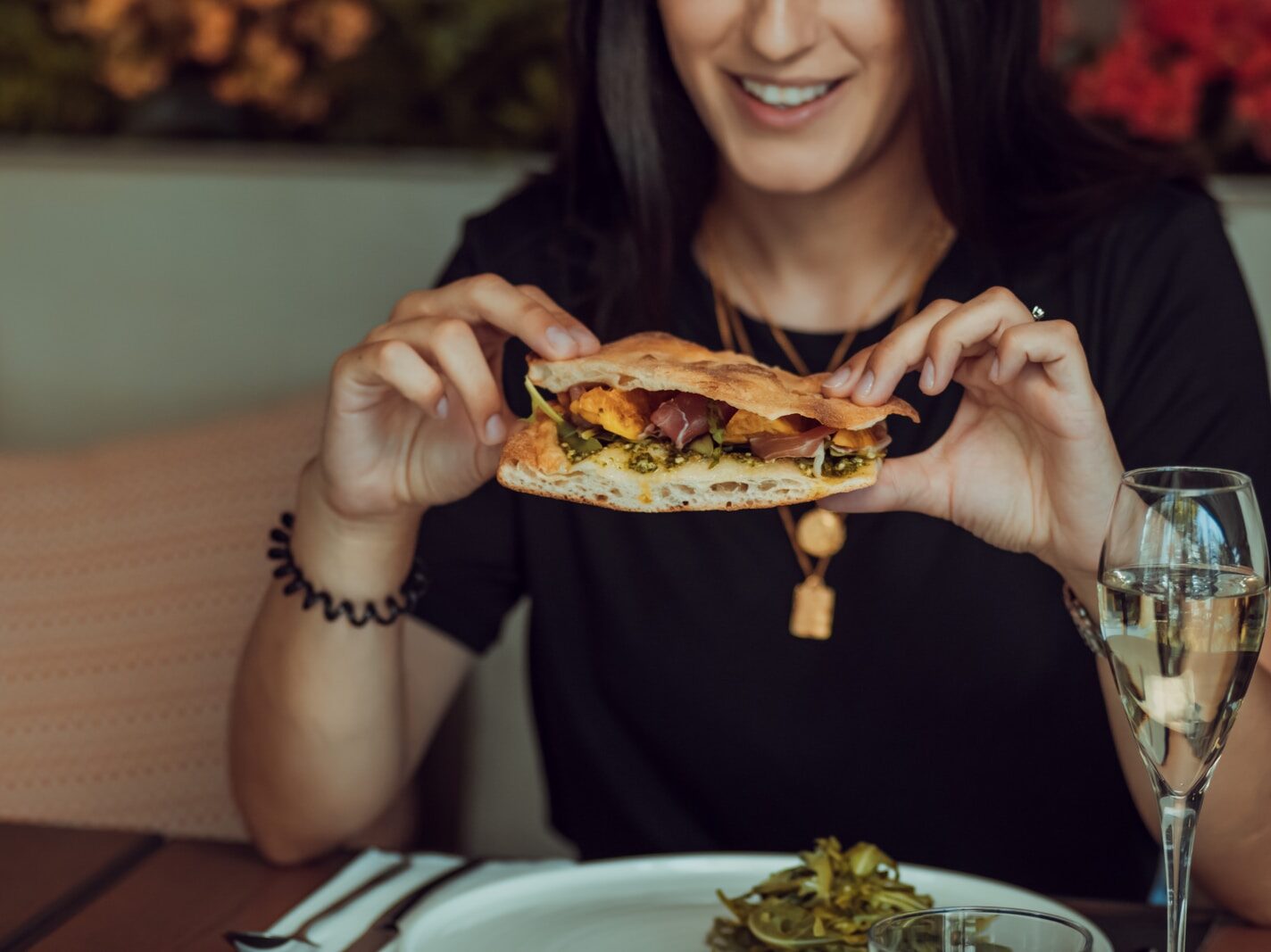 woman in black long sleeve shirt holding a burger