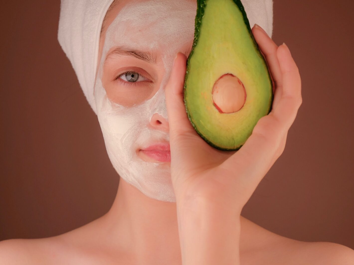 woman with white face mask holding green fruit