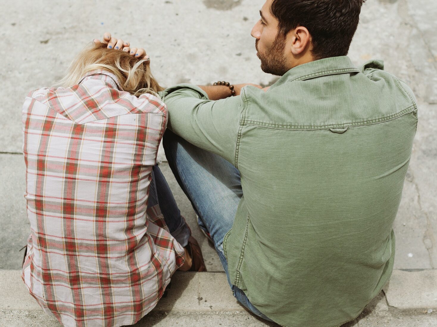 Man and Woman Sitting on Sidewalk