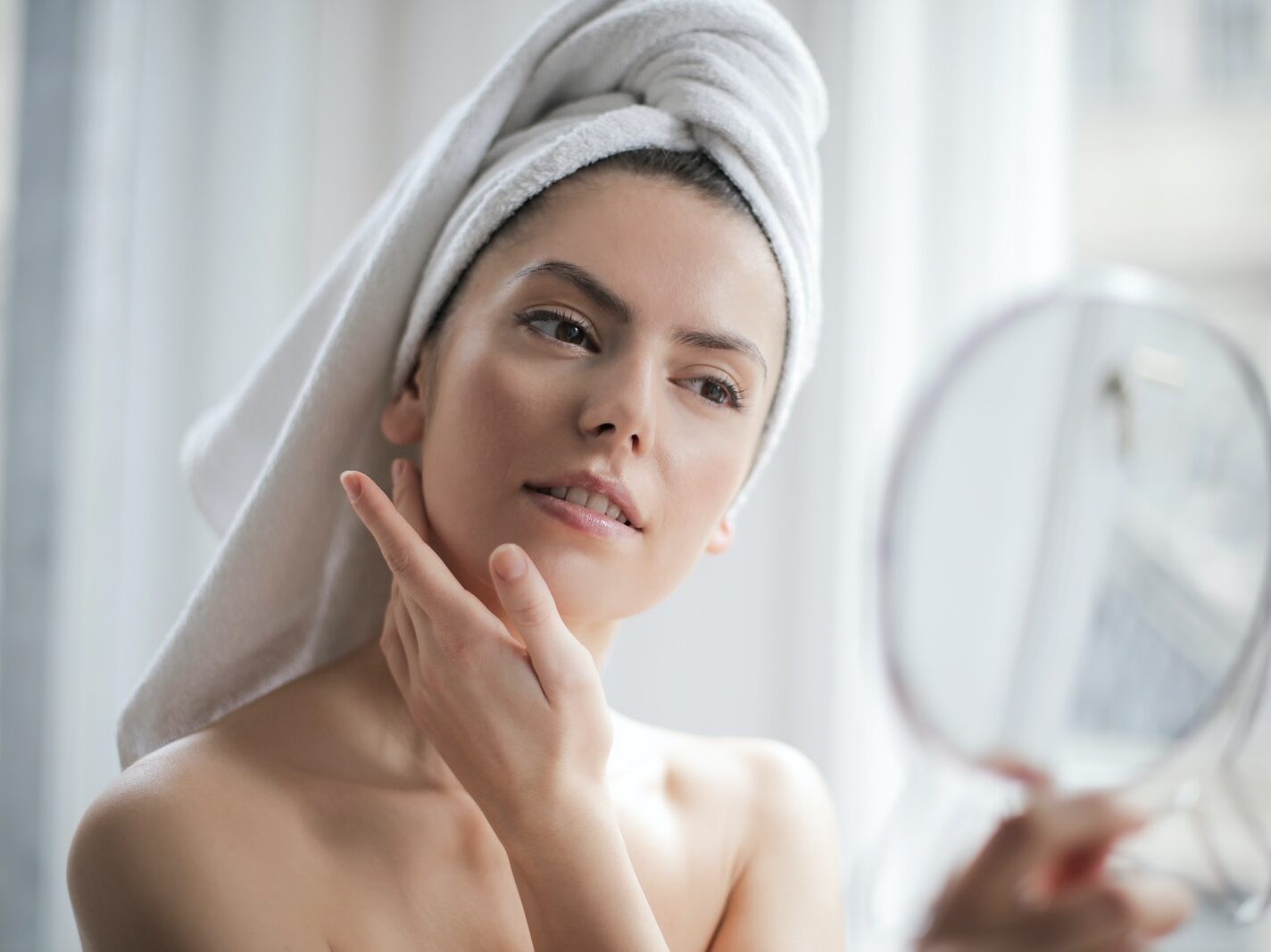 Selective Focus Portrait Photo of Woman With a Towel on Head Looking in the Mirror