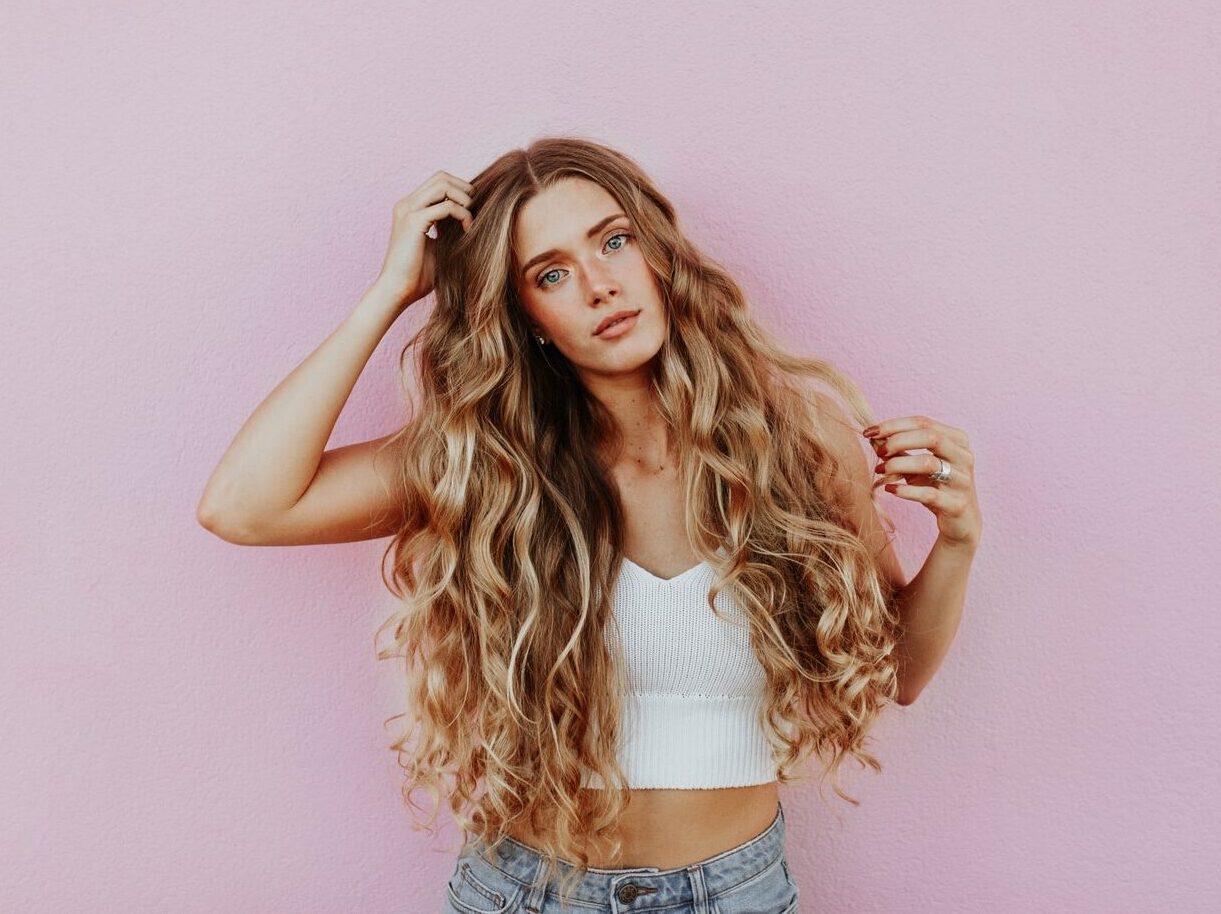 woman standing next to pink wall while scratching her head