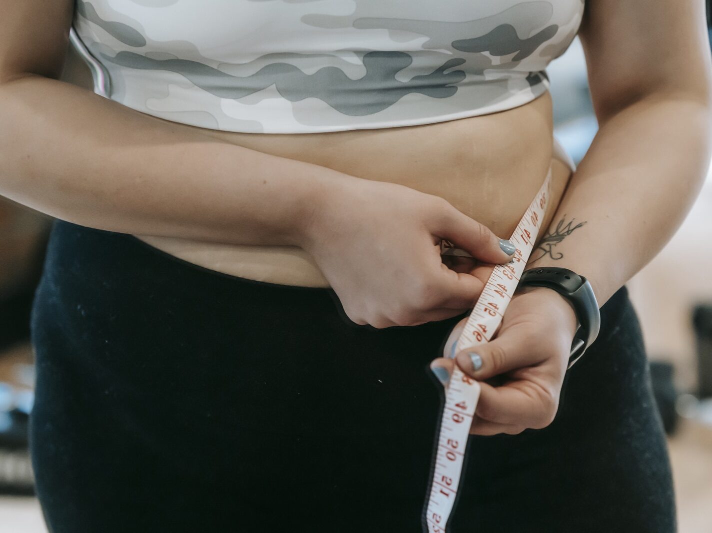 Plump woman in sportswear with measuring tape