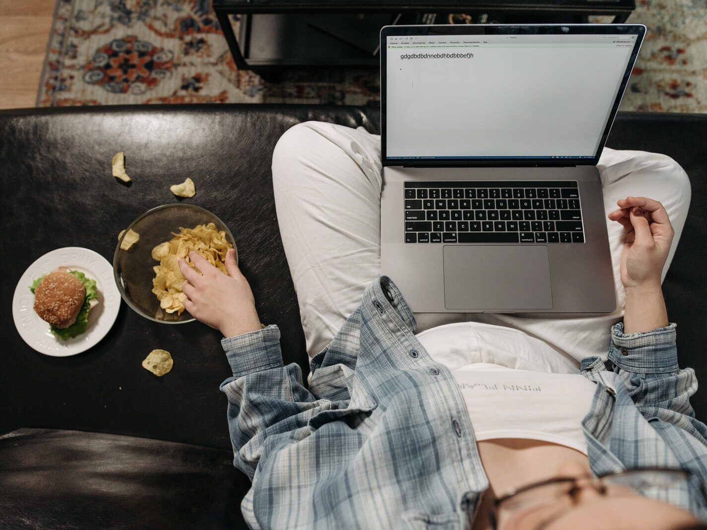 Overhead Shot of a Person Eating Chips while Using a Laptop