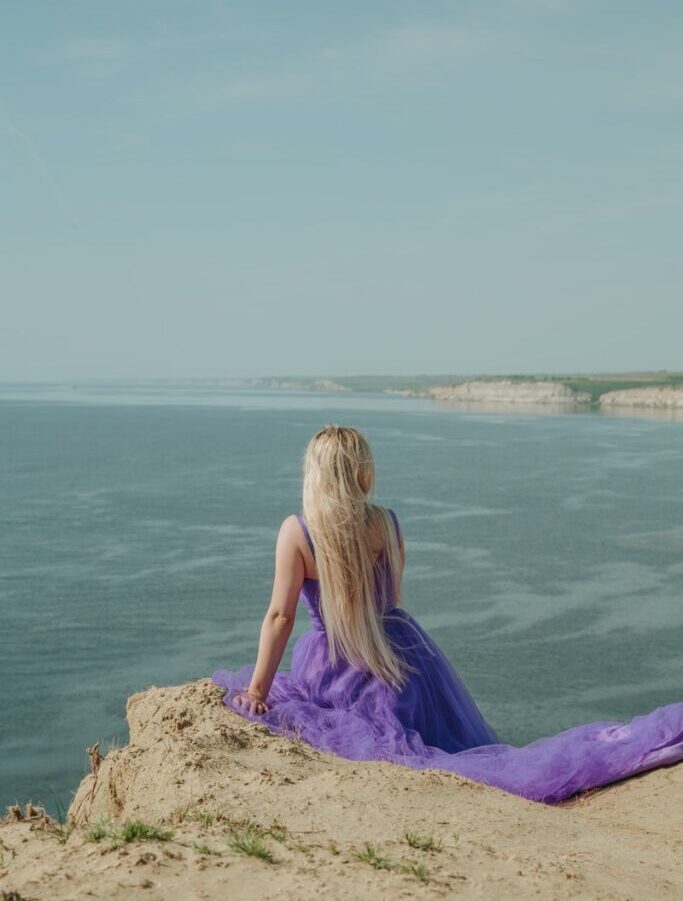 Unrecognizable model contemplating sea from mountain under cloudy sky